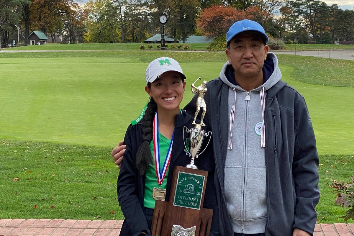 Photo of Catherine Zhang holding an award with her father.
